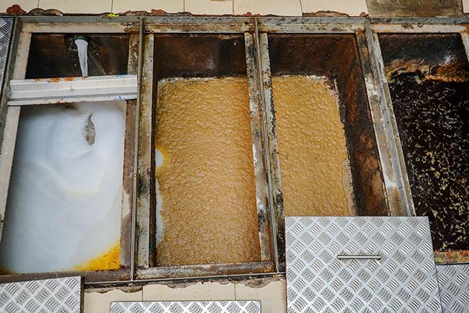 a professional technician working on a grease trap cleaning project